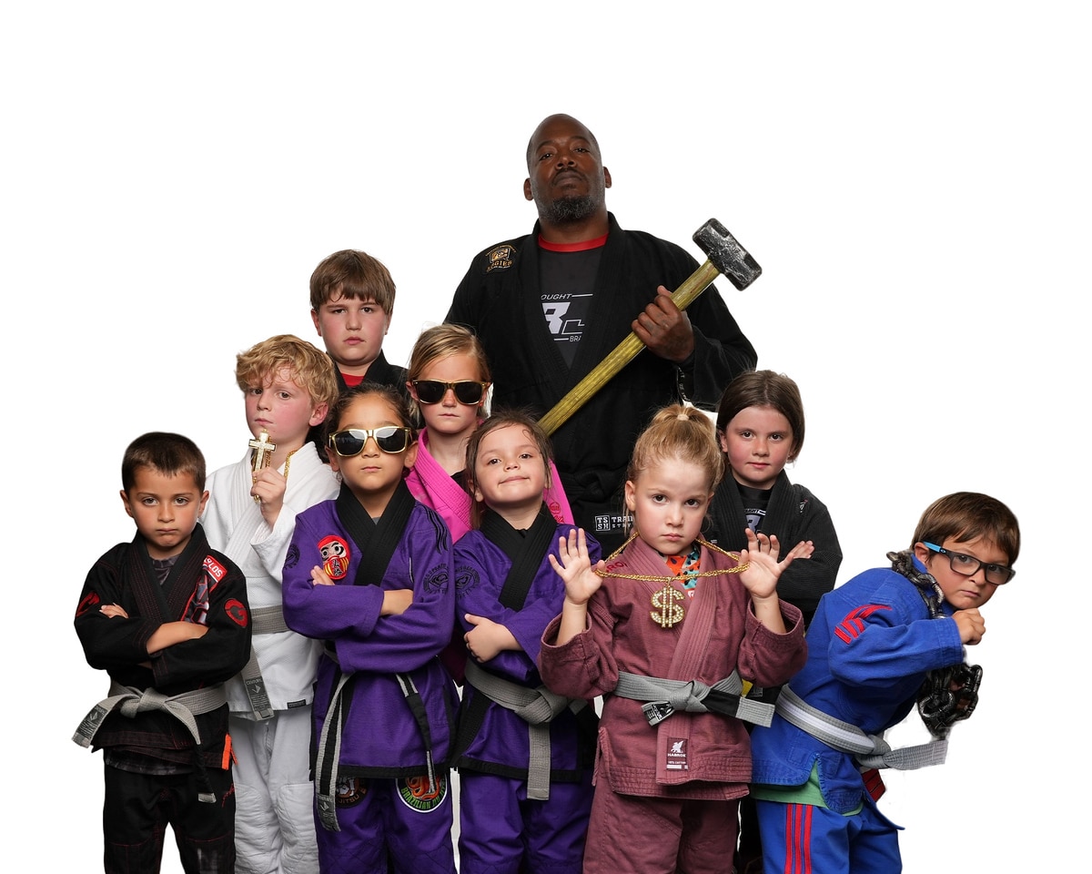 Bjj instructor and young students posing in gi for the camera